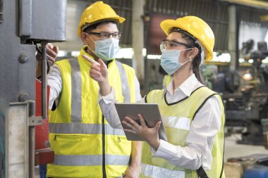 Teknisyenler ve mühendisler yedek parçaların parçalarını sanayi tesislerindeki Tablet örnekleriyle karşılaştırıyorlar. Maske takan teknisyenler.
