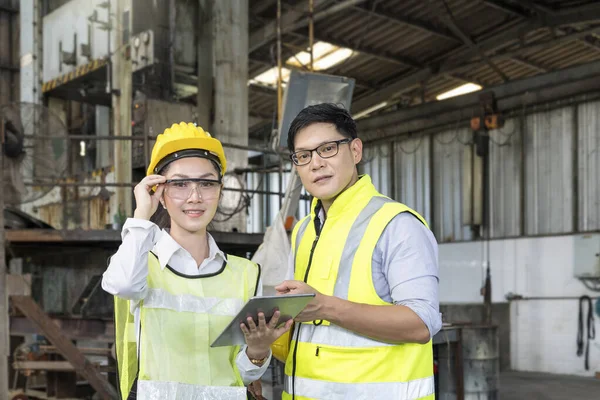 Bir fabrikada iki mühendis. Profesyonel teknisyenler, sanayi tesislerinde çalışan bir tablet bilgisayar kontrolü yapıyorlar..