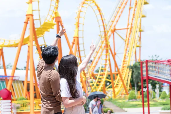 カップルは遊園地でデートに出かけます 遊園地のジェットコースターの近くに見える秋の衣装のカップル — ストック写真