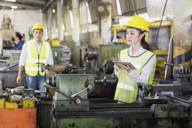 Teknisyenler endüstriyel makineler üzerinde çalışıyorlar. Fabrika atölyesinde tablet ve makine ekipmanı kullanan bir grup fabrika işçisi.
