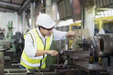 Bir teknisyen mühendisi endüstriyel bir fabrikada çalışmaktan zevk alıyor. Asya makine mühendisi endüstriyel torna makinesini çalıştırıyor.