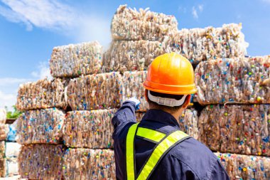 Geri dönüşüm fabrikasındaki bir çalışan, geri dönüşüm sürecine gönderilen plastik atıklara işaret ediyor.