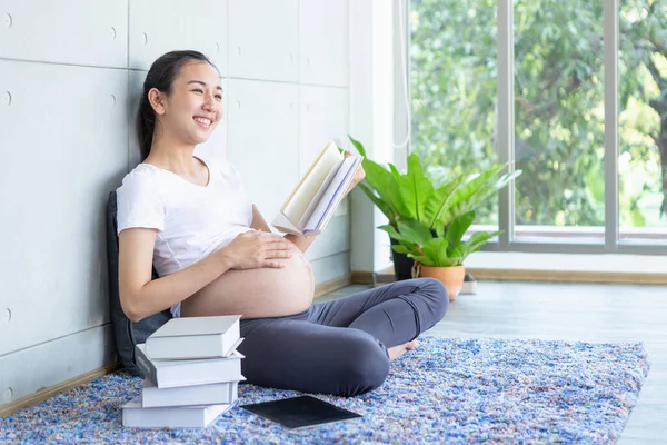 Беременная Женщина Читает Книгу Счастливо Улыбается Гостиной — стоковое фото