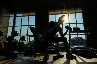Silhouette, Woman are playing dumbbells to build muscle. Muscular young female exercising with dumbbells.
