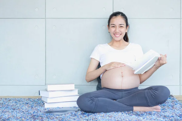 Беременные Азиатские Мамы Читают Книгу Смотрят Камеру — стоковое фото