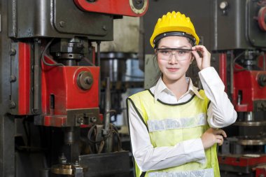 Üretim işçisi. İşi kontrol eden Asyalı işçi. Koruyucu giysiler içinde, kameraya bakıp işten zevk alan neşeli işçilerin portresi..