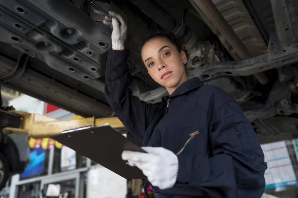 Service repair maintenance concept. African American woman work for auto mechanic in garage checking car engine.