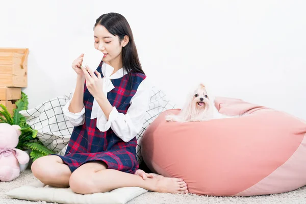 アジアの女性はリビングルームで小さな白いマルタ犬とコーヒーを飲む — ストック写真