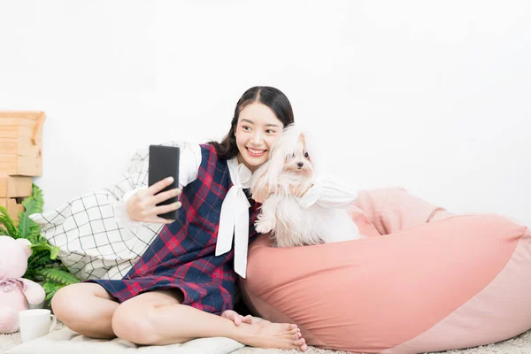 アジア人女性は小さな犬と一緒に自撮りします マルタ犬を飼っている女性が自撮りをする — ストック写真
