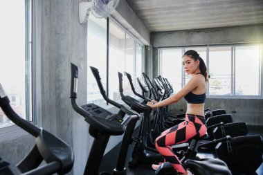 Kadın spora kendini adamıştır. Genç bayan modern spor salonunda eliptik antrenörde çalışıyor..