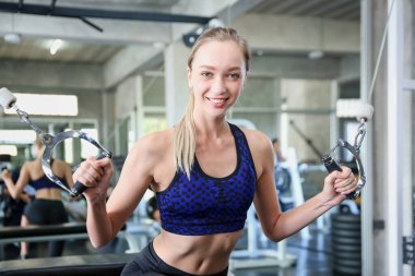 Spor salonunda egzersiz yapan gençler. Spor salonunda spor salonunda spor yapan Asyalı vücut geliştirici spor salonundaki jimnastik kayışlarını kullanıyor..