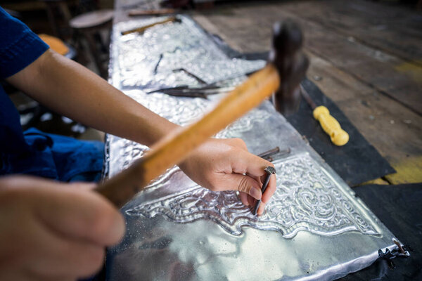 Silversmiths tools on the silver workplace. Silversmith using hammer and steel engraved pattern on silver plate for accessory handmade.