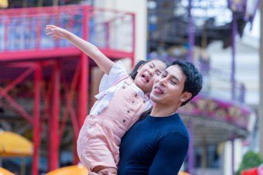 Baba ve kızı lunaparkta oynuyorlar. Lunaparkta aile atlıkarıncada.