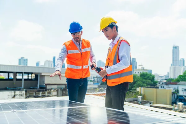 Foreman and Worker maintaining solar energy panel. The supervisor is explaining the installation of the solar panel to the young worker.