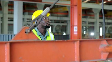 Mühendisler metal levha fabrikasındaki üretim hattını aktif olarak izliyorlar. Bir erkek ve mühendis çalışanları kontrol ediyor..