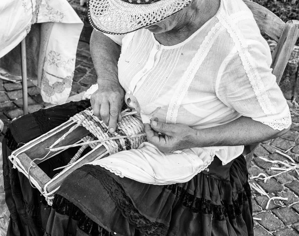 Elderly lady builds hand woven baskets.