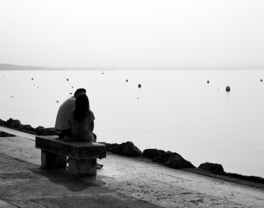 Lakeside arkadan aydınlatmalı tarafından bir bankta oturmuş severler.