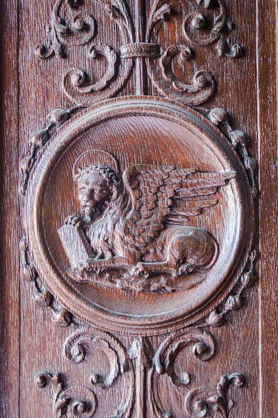 Leão alado gravado no portal de madeira de uma igreja antiga . — Fotografia de Stock