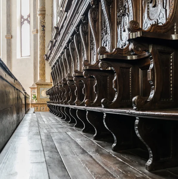 Details of wooden pews next to the altar of a medieval church. Stock Picture
