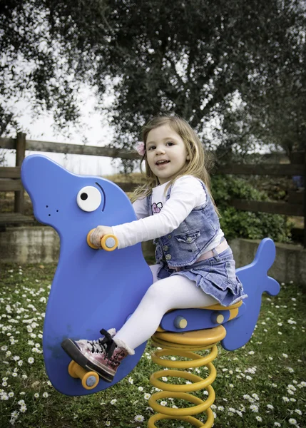 Kind speelt op een blauwe voorjaar zegel in een speeltuin — Stockfoto