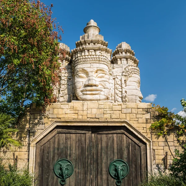 Stone faces of a temple and wooden portal. — Stock Photo, Image