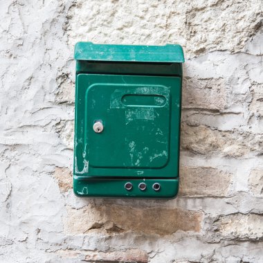 Old green mailbox attached to a stone wall. clipart