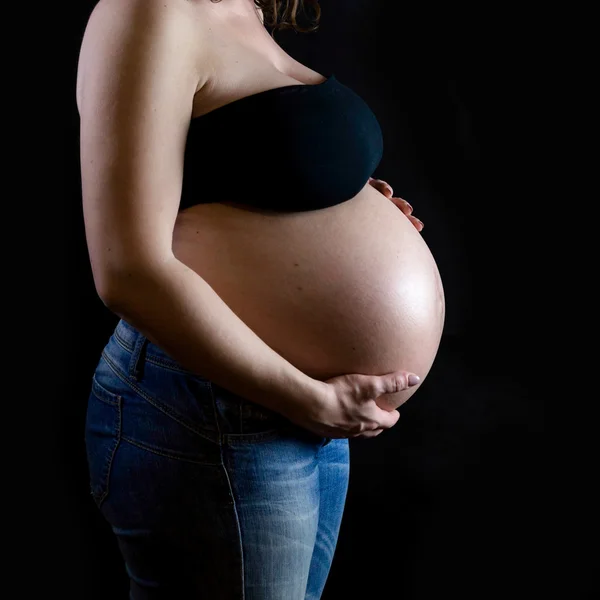 Die Schwangere auf dunklem Hintergrund — Stockfoto