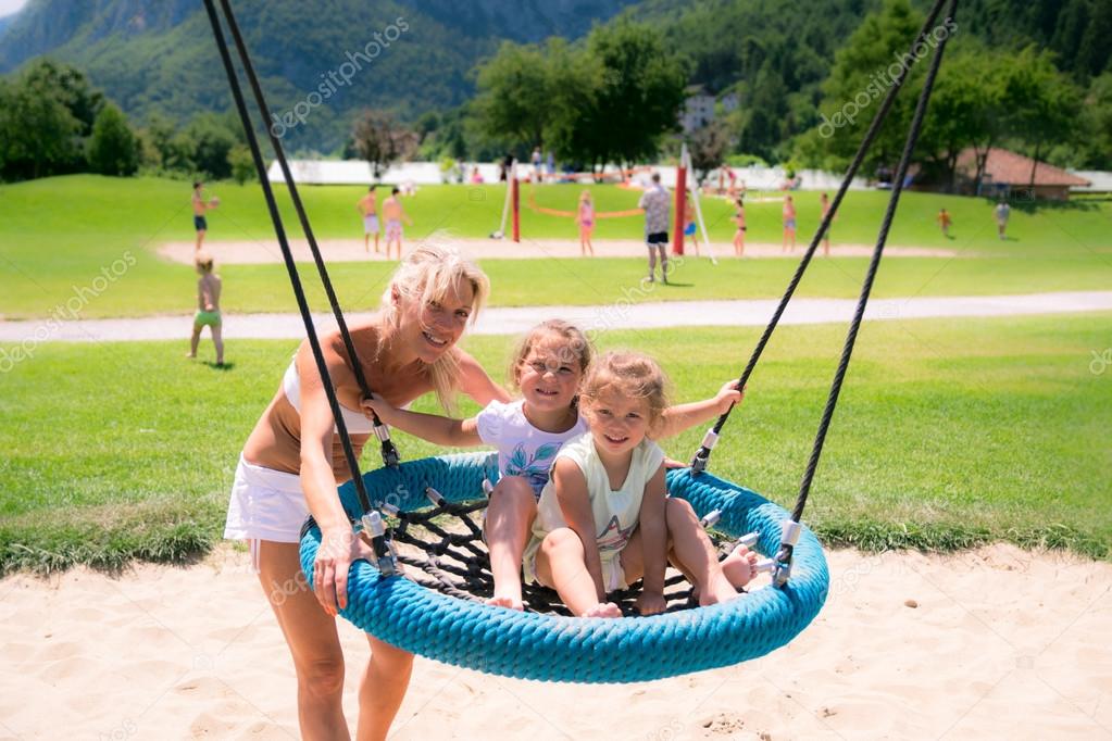 Blonde mom pushes the girls on the swing. Stock Photo by ©Isaac74 99216808