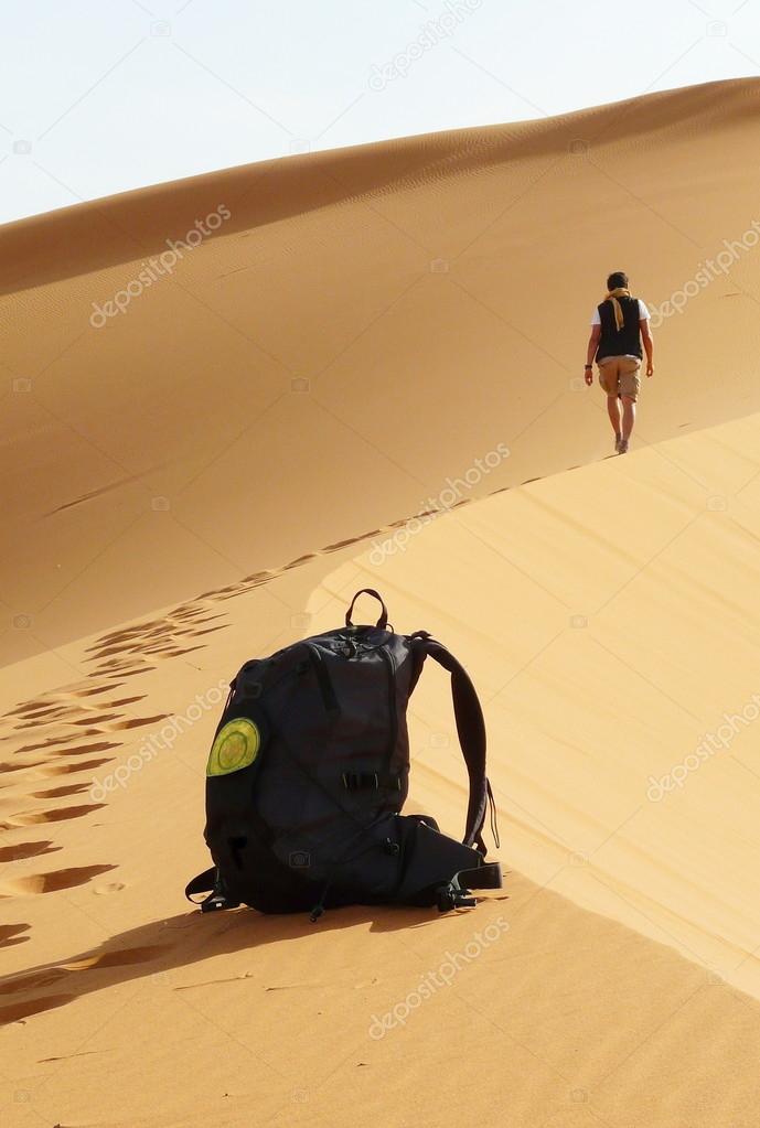 Detail of bag and hiker climbing to the top of the Great Sand Dune in the red dune sea of Erg Chebbi, Morocco