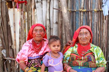 Playón Chico village, Panama - August, 4, 2014: Three generations of kuna indian women in native attire sell handcraft clothes to travelers, San Blas region, Panama. clipart