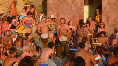 Benirras beach, Ibiza, İspanya - 23 Temmuz 2006: bir sürü insan oynarken davul ve diğer enstrümanlar gün batımını izlemek. Bu geleneksel kutlama tüm Pazar Temmuz ve Ağustos yer alır.