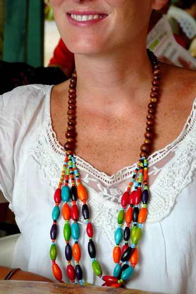 Close up of a wooden necklace worn by a cheerful young woman in Puerto Viejo, Costa Rica.