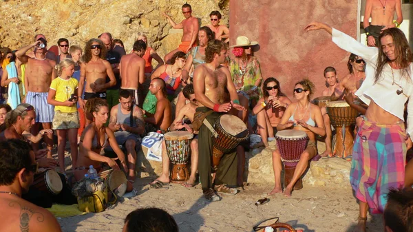 Benirras beach, Ibiza, Spagna - 23 luglio 2006: Molte persone guardano il tramonto mentre suonano la batteria e altri strumenti. Questa tradizionale celebrazione si svolge tutte le domeniche di luglio e agosto . — Foto Stock