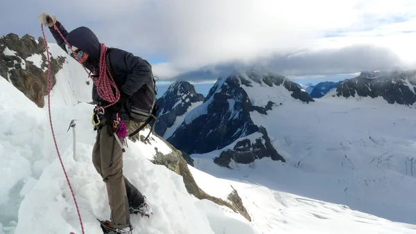 Lonely climber picking up a rope over a ridge while climbing Jungfrau moutain. Mönch and Eiger summits can be found far beyond, Switzerland — ストック写真