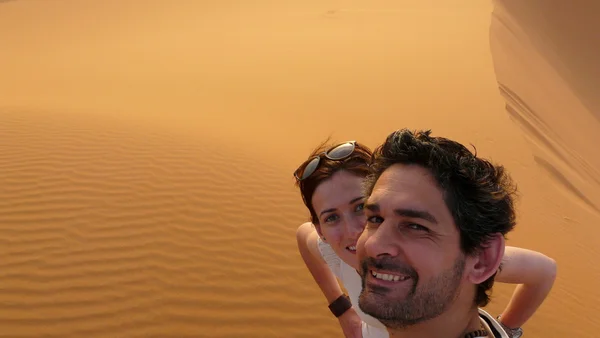 Una joven pareja tomando una foto mientras sube a la cima de la Gran Duna de Arena en el mar de la duna roja de Erg Chebbi, Marruecos . — Foto de Stock