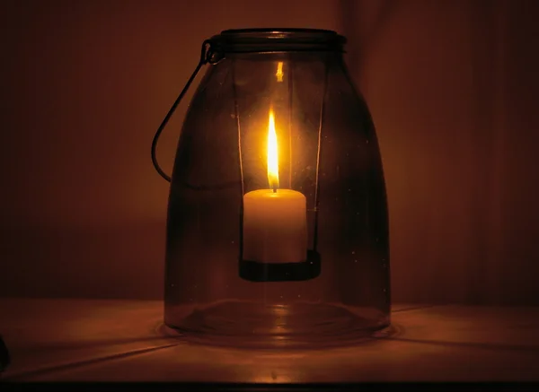 Close up of a burning candle placed inside a n ancient glass recipient — Stock Photo, Image