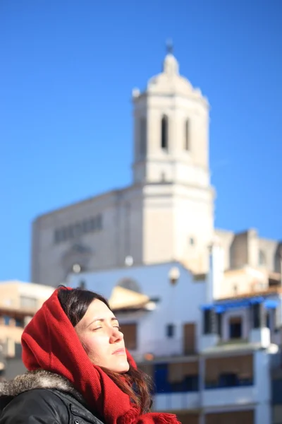 Πορτρέτο μιας νεαρής όμορφης γυναίκας που φοράει κουκούλα με αρχαία κτίρια προς τα πίσω κατά τη διάρκεια ενός κρύου χειμερινού πρωινού στη Girona της Ισπανίας — Φωτογραφία Αρχείου