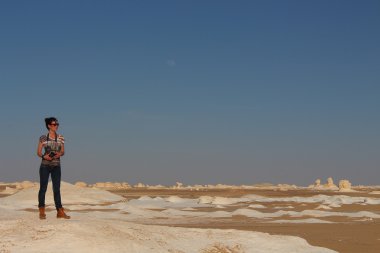 Young beautiful girl takes a picture in the middle of the amazing White desert close to Farafra oasis in Egypt clipart