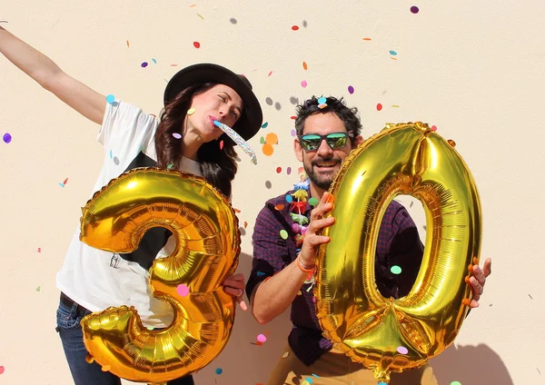 Bir otuz yıl doğum günü büyük altın balonlarla ve kağıt havada renkli küçük parçaları çift kutluyor.