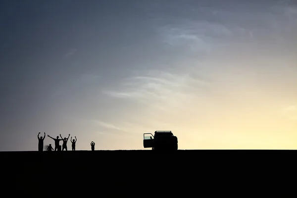 Um pacote de aventureiros saúda a partir do topo de uma grande duna de areia enquanto desfruta de um belo pôr do sol de verão em Dakhla Oasis, Egito — Fotografia de Stock