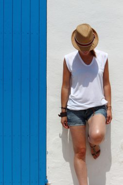 Genç kadın mavi bir ahşap kapı tipik bir köyde bina, Formentera, Balearic Islands, İspanya yakın dinlenme