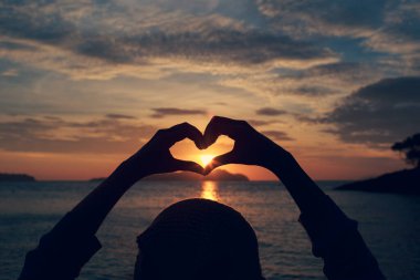 Sevgililer Günü kalp el kavramı kalp şeklinde kadın ellerini soyut bir stil ile bulanık bir gökyüzü arka planda siluet tarzı