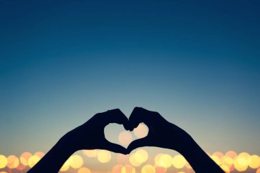 Sevgililer Günü kalp el kavramı kalp şeklinde kadın ellerini soyut bir stil ile bulanık bir gökyüzü arka planda siluet tarzı