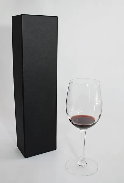 En lyxig svart närvarande väska och ett glas vin separerade på vit bakgrund Stockfoto