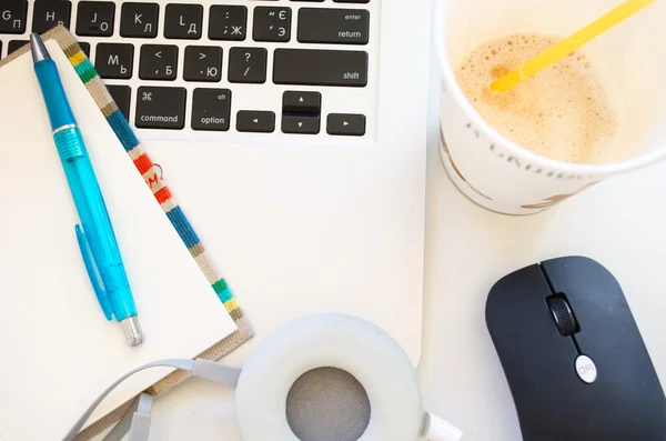 Dizüstü bilgisayar, fincan kahve, Notepaper, kalem ve kulaklık beyaz masada. Üstten Görünüm