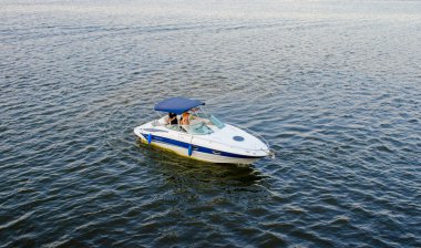 Beyaz ve mavi Motorlu tekne su gün batımında