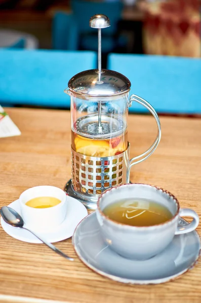 Cup of tea and teapot on wooden table in cafe — Stock Photo, Image