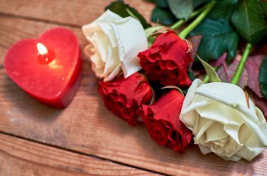 ahşap arka plan üzerinde kırmızı mum ile kırmızı gül demet