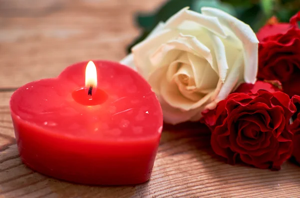 ahşap arka plan üzerinde kırmızı mum ile kırmızı gül demet