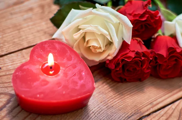 ahşap arka plan üzerinde kırmızı mum ile kırmızı gül demet